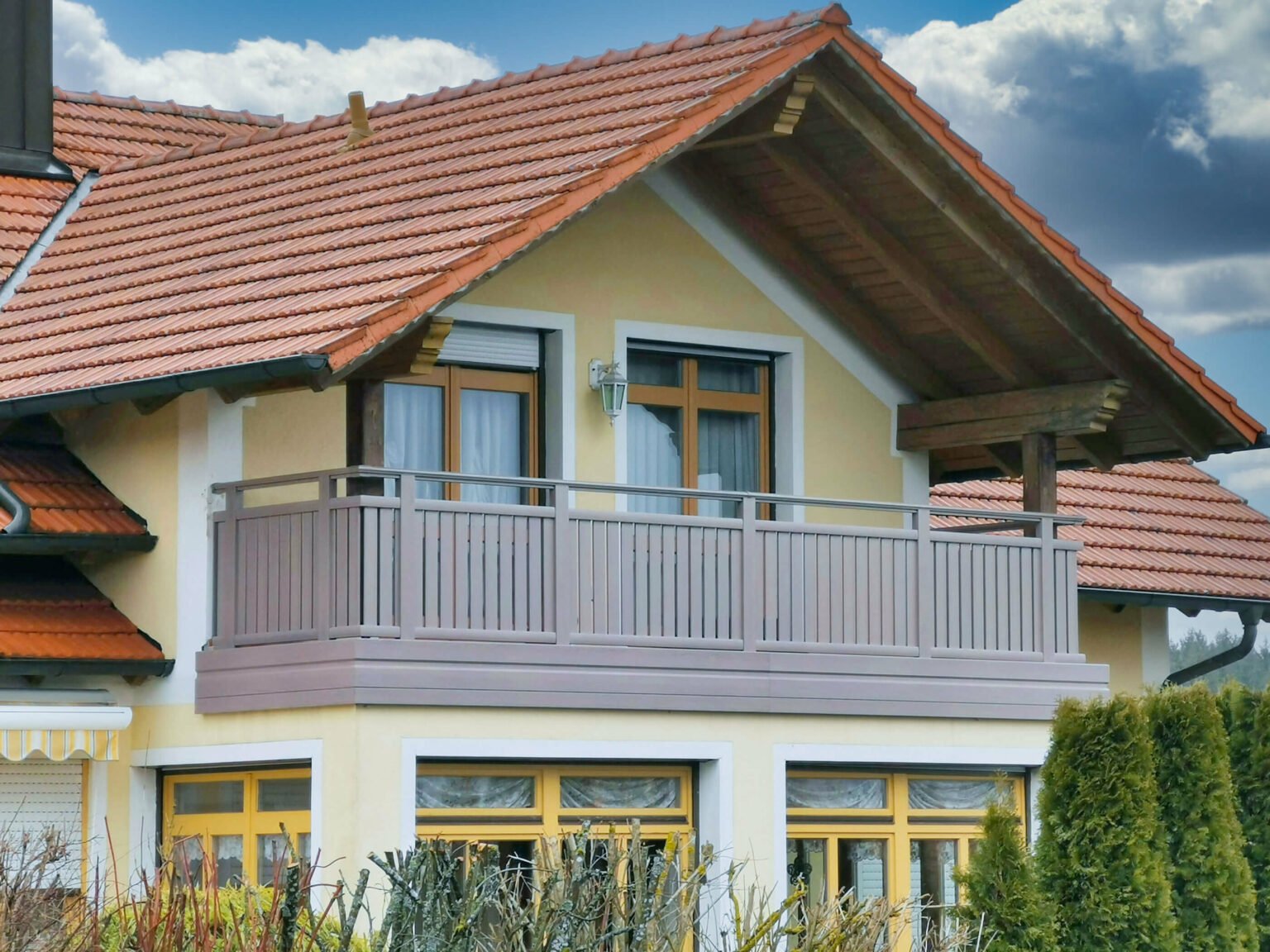 Gelbes Haus mit rotem Dach mit Alu Classic Vilshofen Balkongeländer